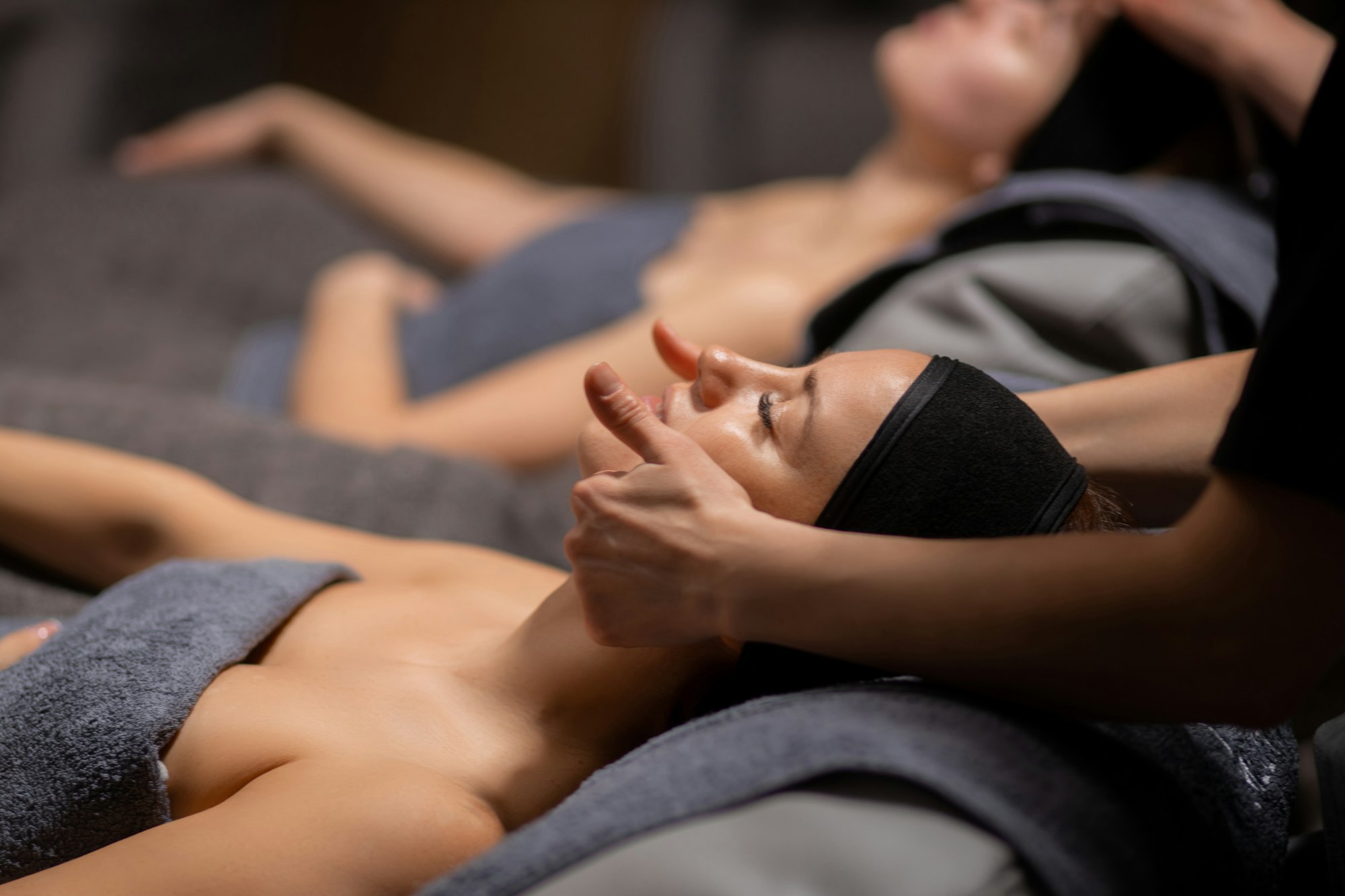 two women get face and neck massage in spa salon